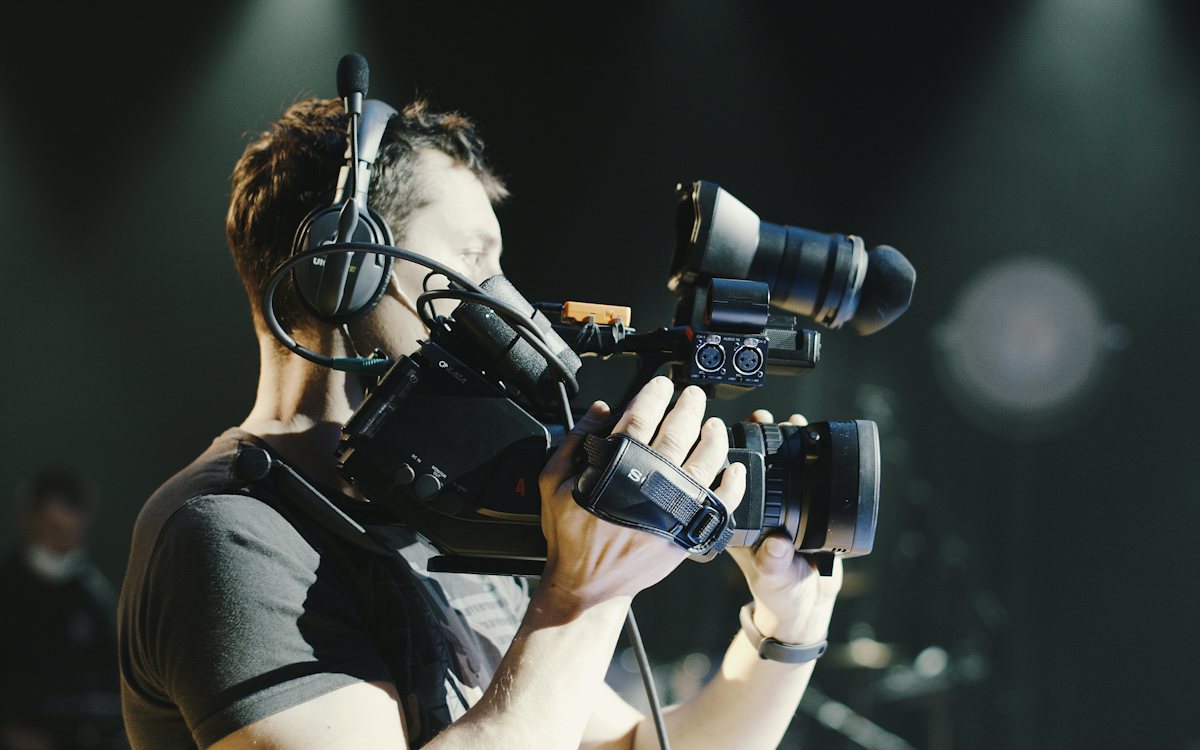 Camera operator with headphones working a cinema camera on set